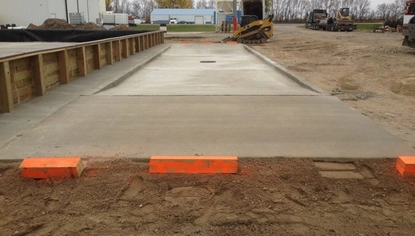 Concrete load pad with integrated drainage installed at an industrial facility to support loading operations and spill containment.