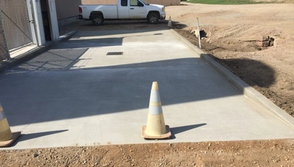 Concrete load pad with integrated trench drain beside an industrial building, designed to support equipment access and spill containment.