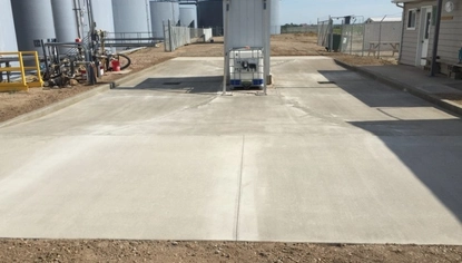Concrete load pad with trench drains installed between storage tanks and equipment, providing spill containment and liquid collection.