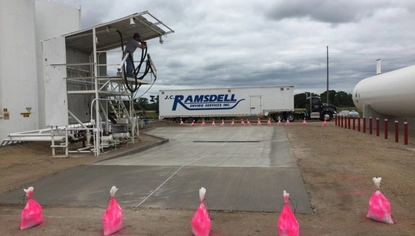 Concrete load pad with integrated drainage beneath a tanker loading station, designed to capture spills during liquid transfer operations.