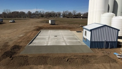 Concrete load pad with integrated drainage installed beside storage tanks and support buildings for spill containment and liquid handling.